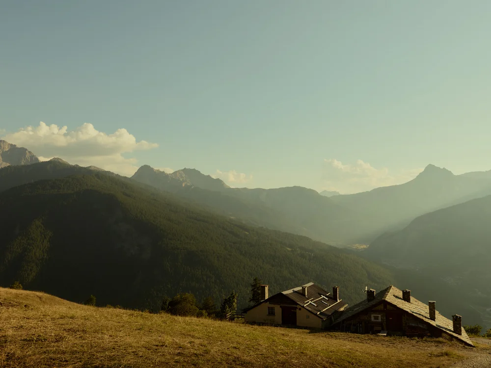 Baita Horres · Luxury Mountain Chalet · Bardonecchia Baite alpine su un prato davanti a una valle montana illuminata dal sole