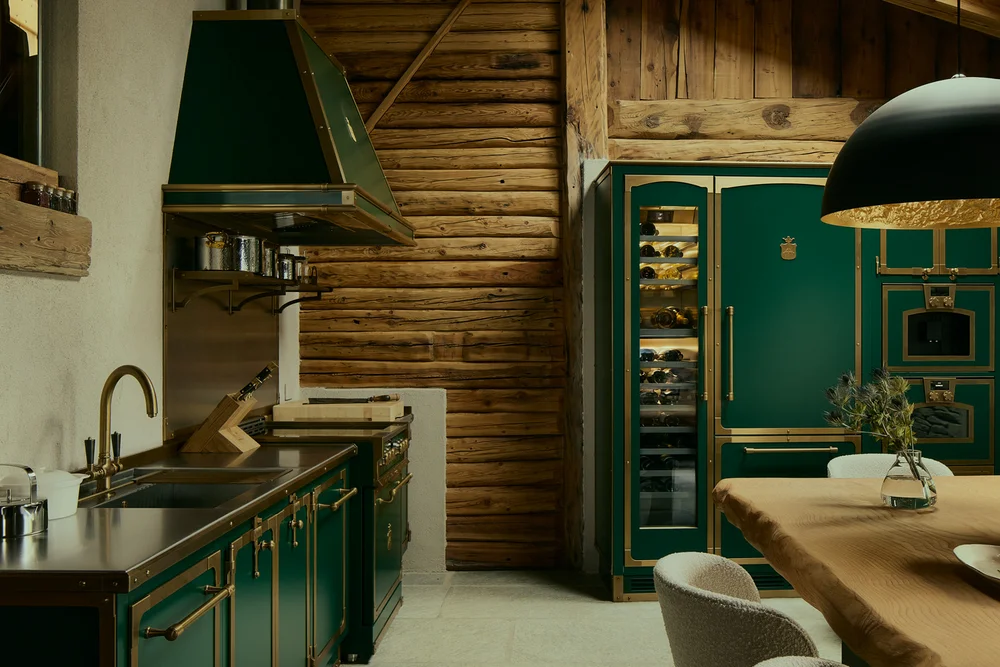 Cucina rustica con armadi verdi, travi in legno a vista e tavolo da pranzo