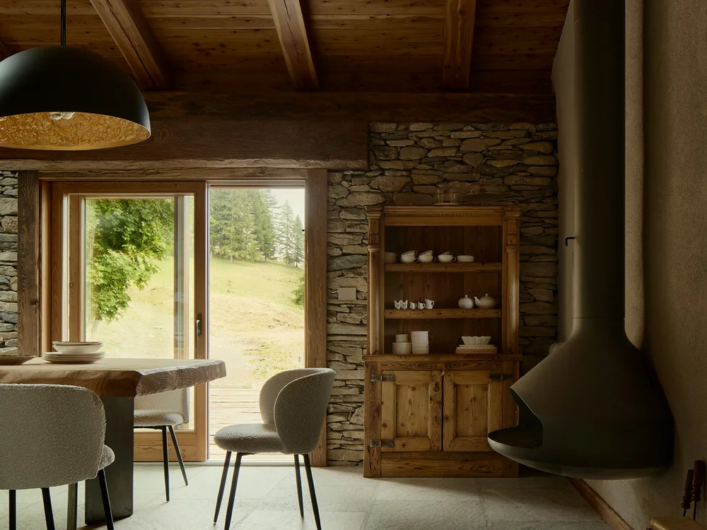 Baita Horres · Luxury Mountain Chalet · Bardonecchia Sala rustica con soffitto in legno, parete in pietra, camino sospeso e tavolo vicino alla finestra