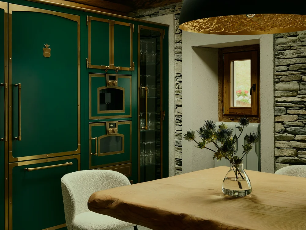 Baita Horres · Luxury Mountain Chalet · Bardonecchia Sala da pranzo con tavolo in legno, mobili verdi, pareti in pietra e lampada a sospensione