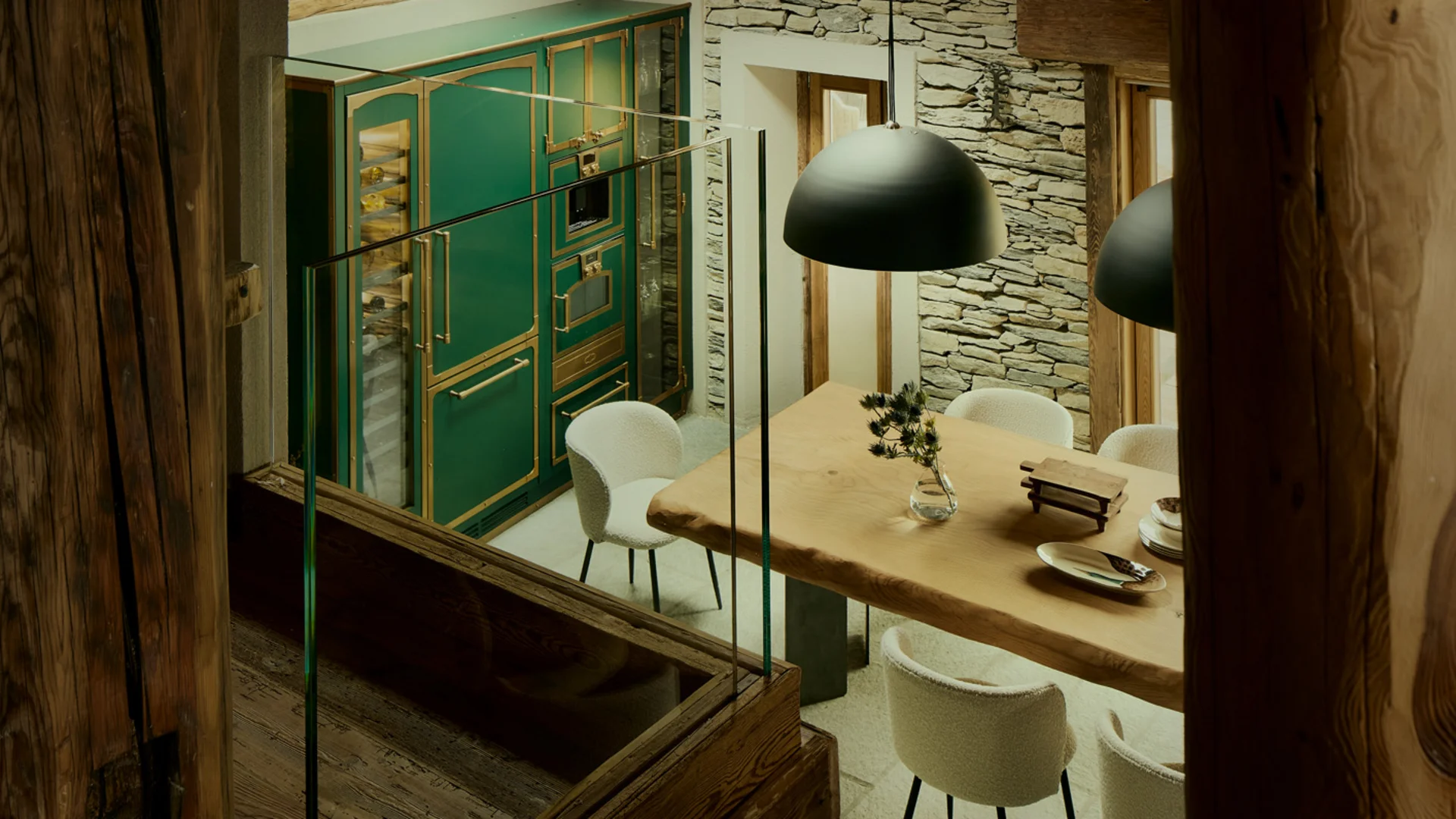 Sala da pranzo rustica con travi in legno, parete in pietra, mobili verdi e tavolo apparecchiato