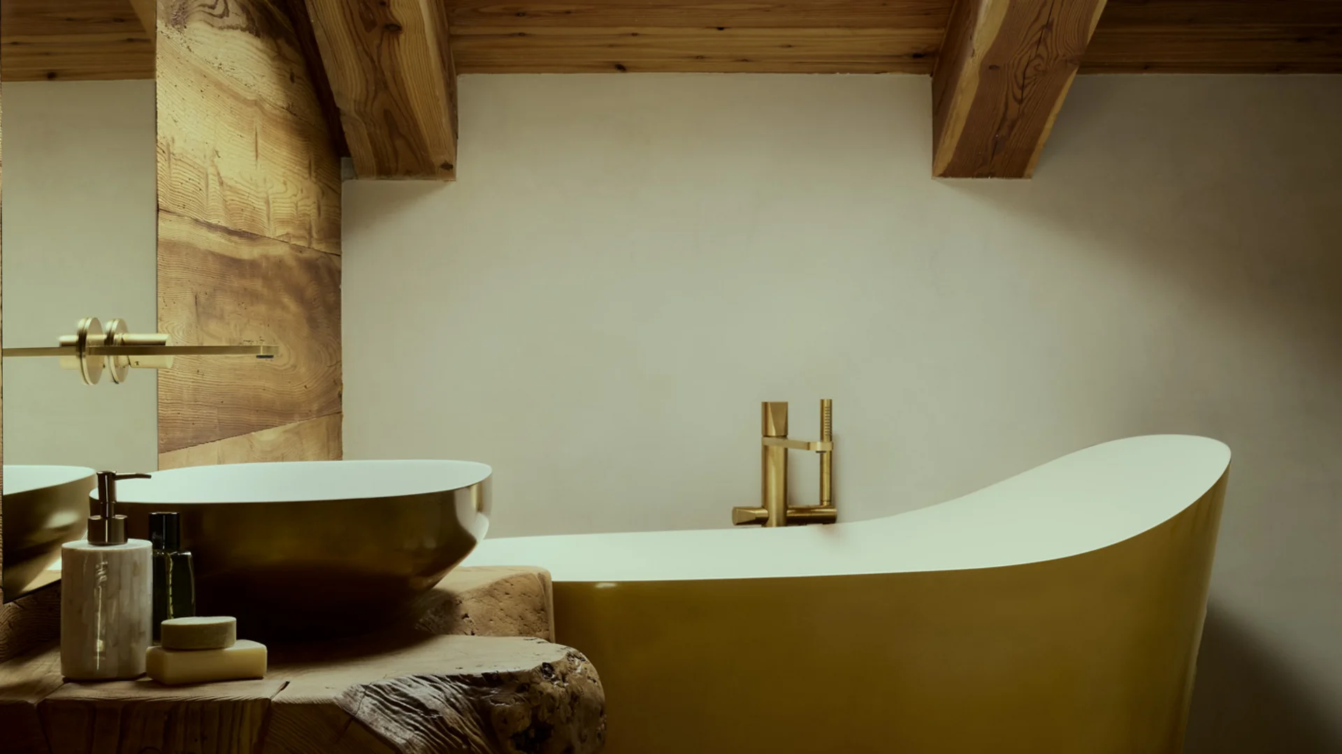 Vasca da bagno freestanding e lavabo su mobile in legno sotto un soffitto con travi e lucernario